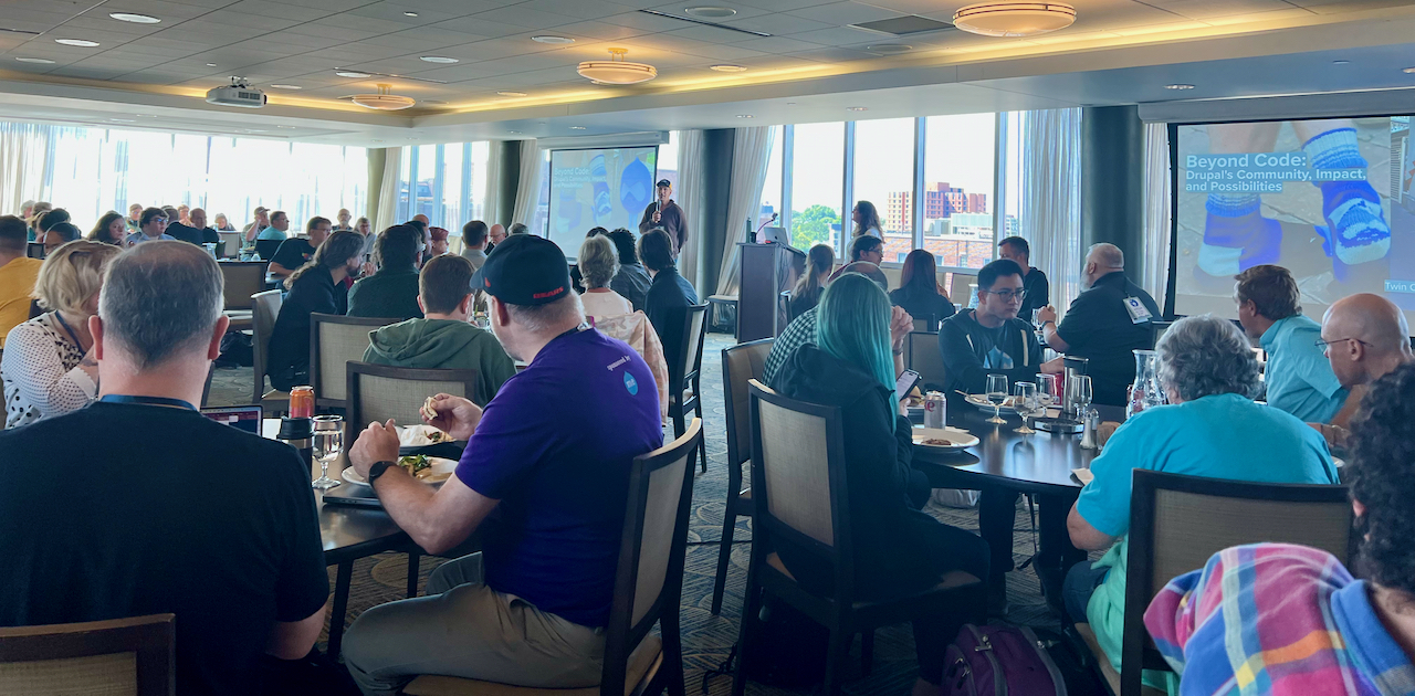 group of people seated around tables watching a presentation