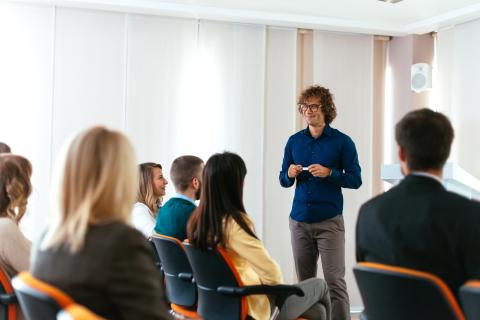 young male adult giving a casual presentation in front of a group